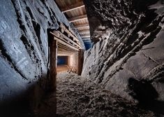 an underground tunnel with rocks and dirt on the sides, leading to another cave entrance