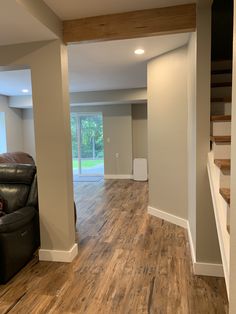 an empty living room with hard wood flooring and stairs leading to the front door