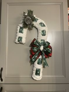 a christmas wreath hanging on the front door with ribbon and pom - poms