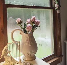 a vase with pink roses in it sitting on a window sill