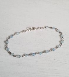 The prettiest little bracelet you'll be reaching for everyday. Dainty natural Aquamarine stones are wired wrapped together. Simple style to wear alone or layered with others for a unique look of your own. Details: * Natural Aquamarine stones * Sterling Silver Clasp * Wire is Sterling Silver with a rhodium plating * Great gift idea * Stack them for a unique look Aquamarine is a stone of enlightenment and spiritual awareness. Natural aquamarine can help soothe a stressed mind, comfort a troubled h Handmade Delicate Blue Bracelets, Delicate Adjustable Hand-strung Bracelets, Delicate Adjustable Hand-strung Bracelet, Handmade Dainty Rosary Bracelet With Round Beads, Dainty Handmade Rosary Bracelet With Round Beads, Handmade Dainty Rosary Bracelet, Delicate Adjustable Bracelets With Natural Stones, Handmade Adjustable Dainty Sterling Silver Bracelet, Handmade Dainty Adjustable Sterling Silver Bracelet