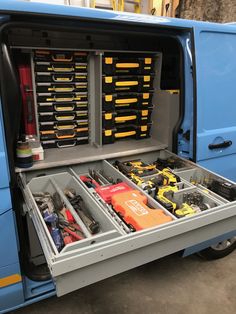 a blue truck with tools in it's compartment and other items inside the back