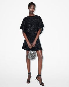 Sparkle all season long. The Ivy Top has a flowing shape that boasts a round neck and delicately draped sleeves. It's relaxed-fitting and cropped to create an elevated structure. Elegant gems, sequins and bead embellishments are a luxe touch. Dress this up with the matching skirt or fitted pants (don't forget a statement metallic heel, now that's a look).  This top is designed to a relaxed fit Keyhole button closure at the back of the neck Round neck Short sleeves Cropped Draped sleeves and heml Embellished Crop Top, Draped Sleeves, Fitted Pants, Drape Sleeves, Metallic Heels, The Ivy, Embellished Top, Going Out Outfits, Guest Outfit