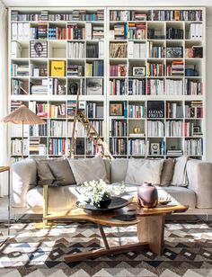 a living room filled with furniture and lots of books on the shelves in front of it