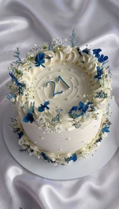 a birthday cake with white frosting and blue flowers on the top is decorated with a number twenty