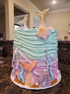 there is a cake decorated with mermaids and seashells on the counter top