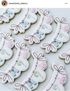 decorated cookies are arranged in rows on a white table top, with ribbons and bows