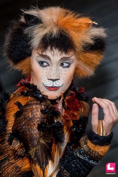 a woman with cat makeup on her face and hair is posing for the camera while wearing an animal costume