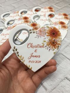 a hand holding a white heart shaped ornament with flowers on it and the words, christmas & janes