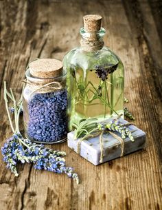 two bottles filled with lavender flowers next to each other on top of a wooden table