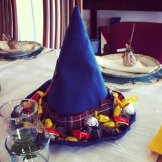 a blue hat sitting on top of a table next to glasses and plates filled with candy