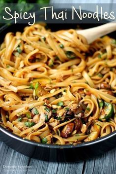 a pan filled with noodles and mushrooms on top of a wooden table