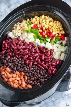 the slow cooker is filled with beans, corn, and other vegetables in it