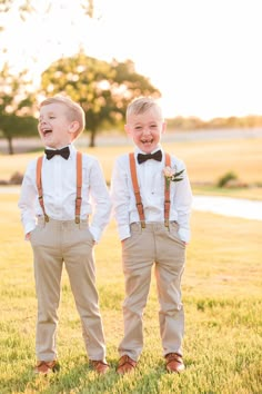 two young boys wearing suspenders and bow ties are standing in the grass with their mouths open