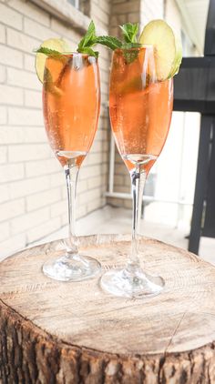 two champagne flutes with lime and mint garnish sit on a wooden table