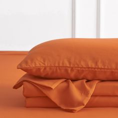 an orange sheet and pillow on top of each other