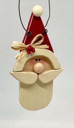 a wooden santa claus ornament hanging from a string with a bow on it's head