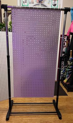 a purple and black metal pegboard on top of a wooden floor next to a wall