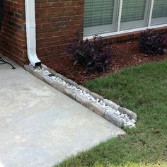 the side of a brick house with grass and flowers