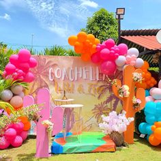 an outdoor party with balloons and decorations on the grass, in front of a sign that says cocoholia beach