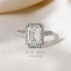 an emerald cut diamond ring with diamonds surrounding it