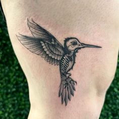 a small bird tattoo on the side of a woman's lower back leg, with wings spread out