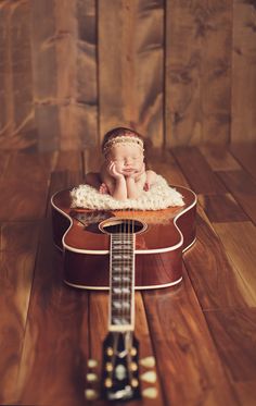 a baby laying on top of a guitar