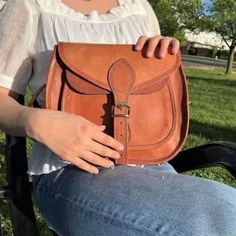 Rustic Goat Leather Crossbody Satchel Bag on model's lap Natural Color Satchel Shoulder Bag For On-the-go, Rectangular Satchel With Leather Strap For On-the-go, Everyday Saddle Flap Bag With Adjustable Strap, Everyday Use Saddle Flap Bag With Adjustable Strap, Daily Use Saddle Bag With Adjustable Strap, Handmade Crossbody Shoulder Bag For On-the-go, Travel Saddle Flap Bag With Adjustable Strap, On-the-go Leather Strap Satchel, Natural Satchel Shoulder Bag With Detachable Strap