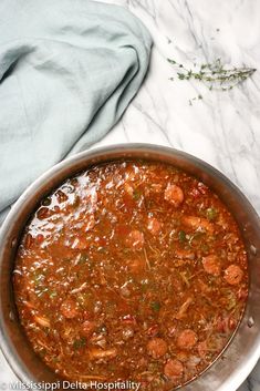 a pot filled with meat and vegetables on top of a table next to a blue towel