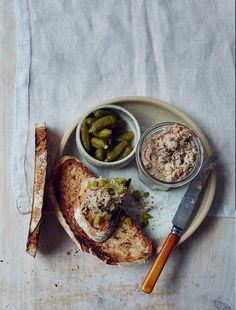 a plate with bread and pickles on it next to a bowl of pickles