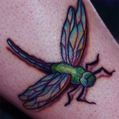 a colorful dragonfly tattoo on the left side of someone's arm and leg