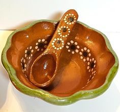 a brown and green bowl with a spoon in it