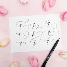 a sheet of paper with calligraphy on it next to some pink tulips