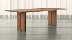 a wooden table sitting on top of a tile floor next to a white curtained window