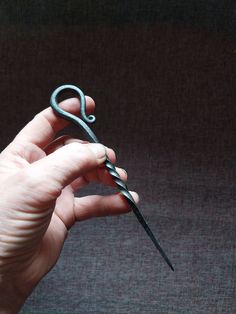 a person holding a pair of scissors in their left hand and the other hand is pointing at it