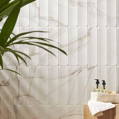 a bathroom with white marble tiles on the wall and two soap dispensers