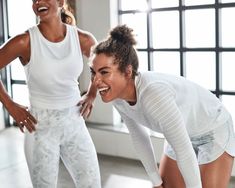 two women in white shirts and leggings laughing