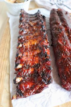 two barbecue ribs sitting on top of a wooden cutting board