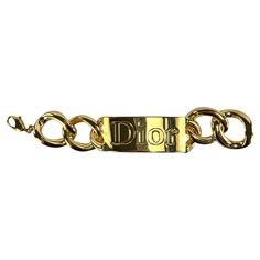 From Christian Dior's Fall/Winter 2000 collection by John Galliano, this gold chain bracelet, showcased on the runway, features the iconic Dior logo in an oversized take on a classic ID bracelet. This curb-link bracelet was featured in multiple images from the season's ad campaign on Raica Oliveira, captured by Nick Knight. The matching necklace is also available on our storefront, completing the statement set from this iconic collection. Approximate Measurements: Width: 1" Length: 7" Elegant Gold-tone Chain Link Jewelry With Logo Plaque, Elegant Gold-tone Chain Link Jewelry, Luxury Gold-tone Metal Bracelet, Designer Gold Metal Chain Bracelet, Designer Gold Chain Bracelet, Designer Gold-tone Chain Bracelets, Luxury Gold Metal Chain Bracelet, Luxury Gold-tone Bracelet With Chain, Designer Gold Chain Bracelets