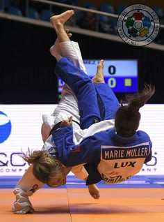 two people in blue and white uniforms are doing tricks on the floor with one person upside down