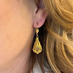 These Intricate Filigree Mid-Century Drop Earrings feature a vintage teardrop chandelier design 14 karat yellow gold. Royal filigree metalwork wears around each pear-shaped charm. Two seashell engravings decorate the front of the lever backings. A milgrain rope and openwork design. The drops measure 1.75 inches long and .25 inches wide. Romantic, radiant, and truly unique. French-inspired Mid-Century drops to lighten up your look! Classic Filigree Chandelier Earrings As Gift, Formal Yellow Gold Chandelier Earrings With Intricate Design, Wedding Filigree Teardrop Jewelry, Classic Filigree Chandelier Earrings For Gift, Teardrop Filigree Jewelry For Weddings, Traditional Gold Teardrop Earrings For Gift, Elegant Teardrop Earrings With Intricate Design, Yellow Gold Teardrop Earrings For Wedding, Fine Jewelry Yellow Gold Earrings With Intricate Design