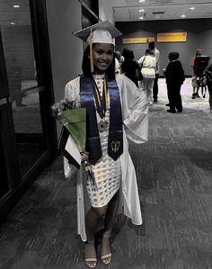 a woman wearing a graduation gown and holding a green umbrella in an office building hallway