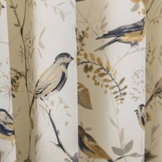 two birds are sitting on the branches of a tree in front of curtains with leaves and flowers