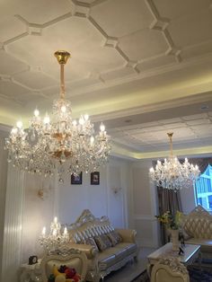 a chandelier hanging from the ceiling in a room with couches and chairs