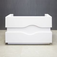 a white reception table sitting on top of a tiled floor next to a gray wall