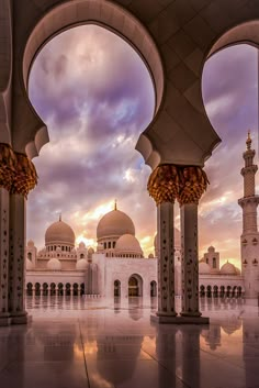 the inside of a building with arches and pillars in front of it at sunset or dawn