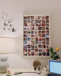 a laptop computer sitting on top of a desk next to a lamp and pictures hanging on the wall