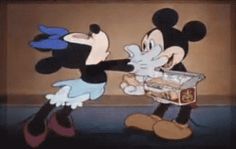 two mickey mouses standing next to each other in front of a box with food