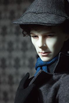 a close up of a mannequin wearing a black hat and coat with a blue scarf