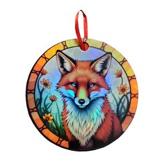 a stained glass ornament with a red fox on it's face and flowers in the background